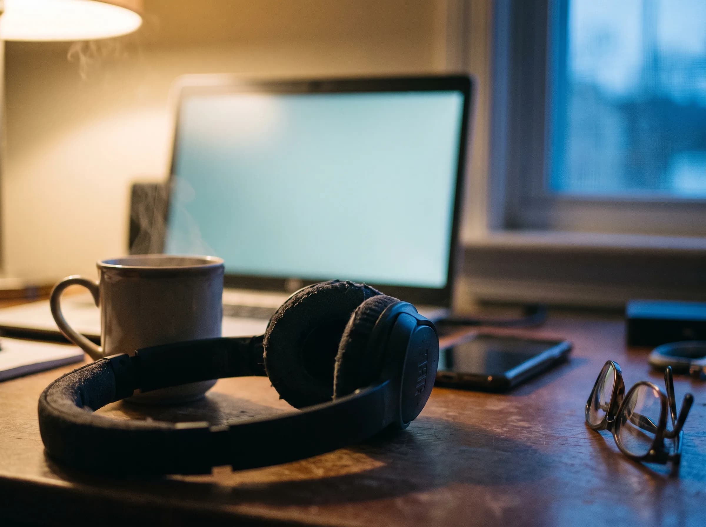 Headphones and a mug of tea on a desk, the quiet minute before an online interview.